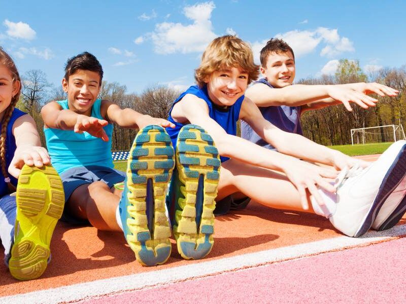Kids sitting and stretching on a running track