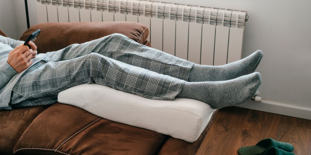 Person sitting on bed with legs elevated